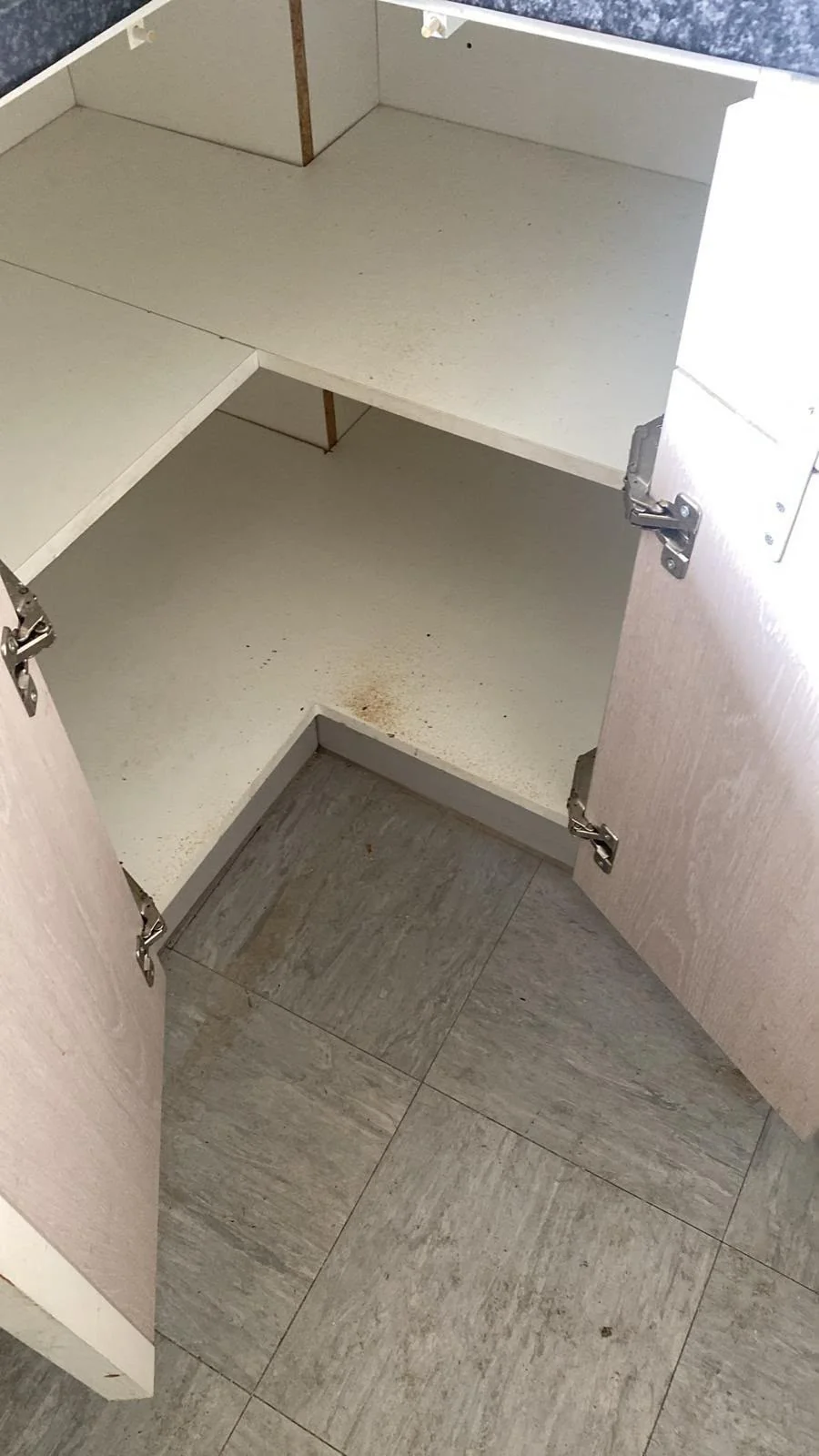 Kitchen cupboard shelves with dirt and crumbs before cleaning