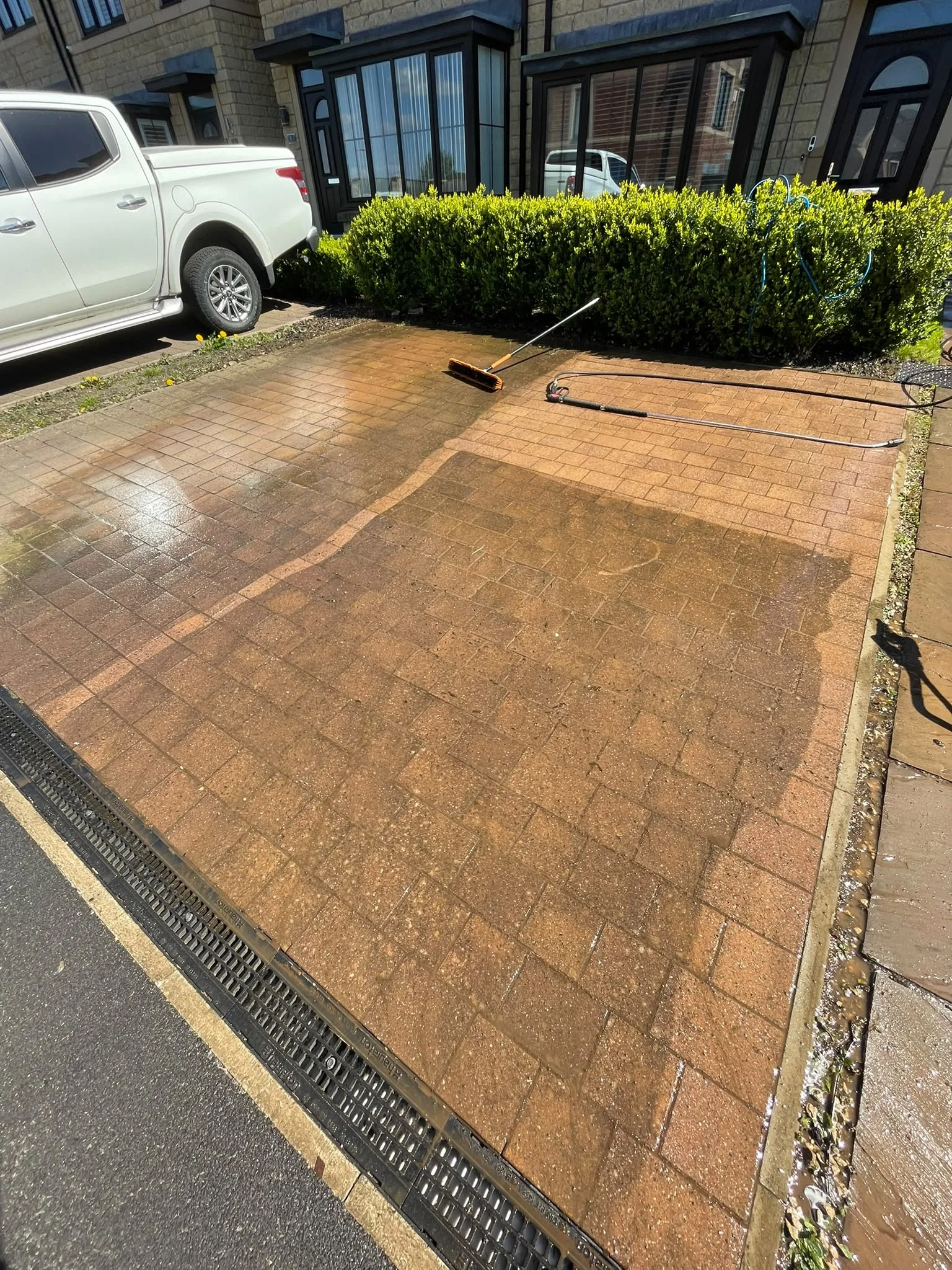 Rotary surface cleaner on a driveway, with clean and dirty sections side by side