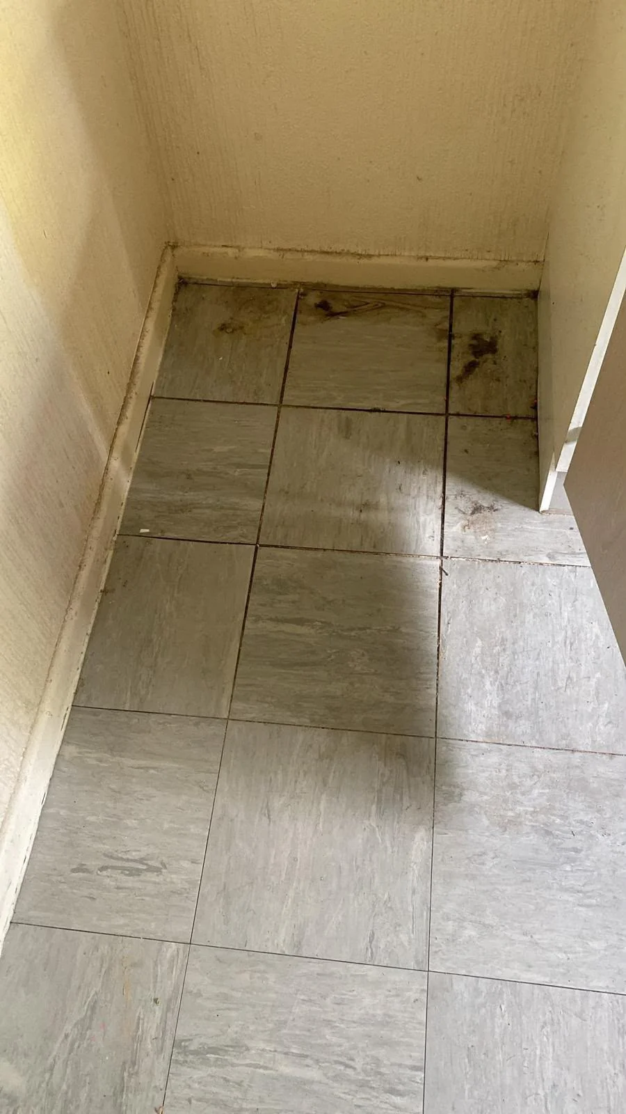 Utility room tiled floor covered in dirt before cleaning