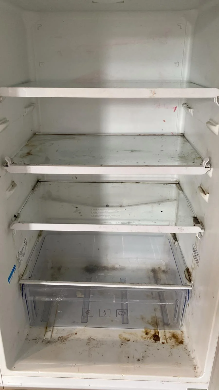 Fridge interior with brown food stains and grime before cleaning
