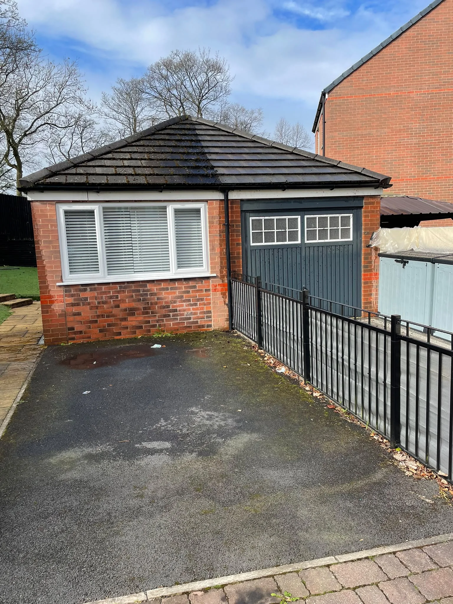 Garage roof half cleaned, with clean and mossy tiles side by side