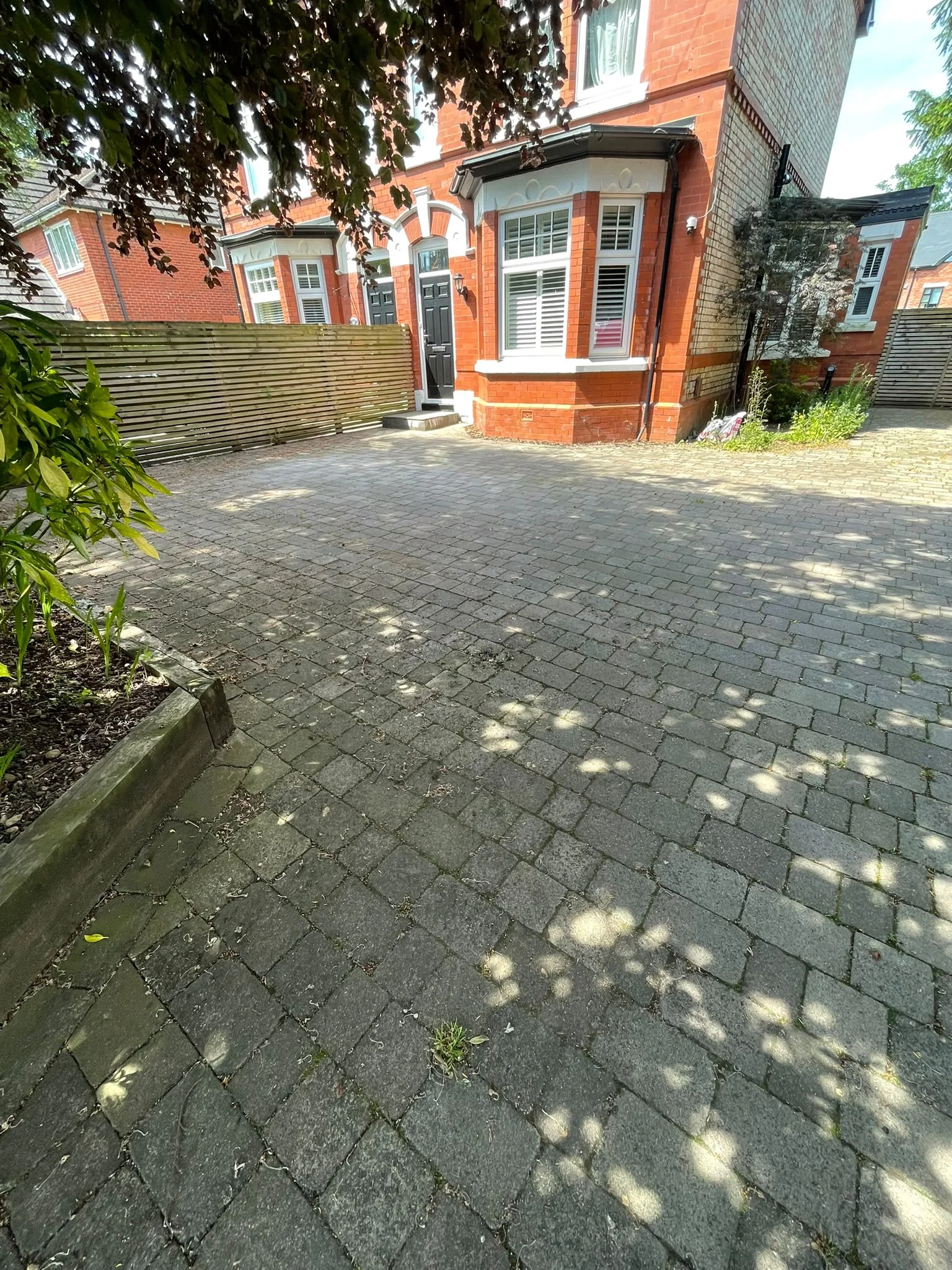 Large block paving driveway with weeds and dirt before cleaning